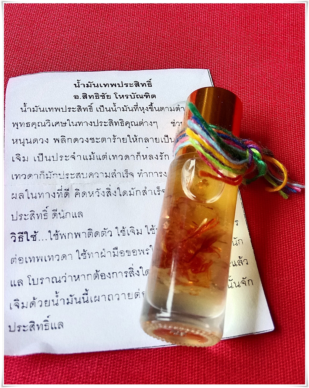 Small glass vial of thai buddhist fortune oil with red floral inclusion and multicolor cord on Thai prayer paper