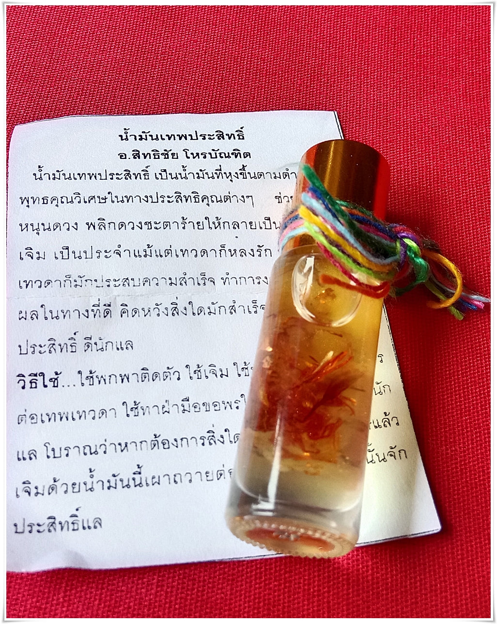 Small glass vial of thai buddhist fortune oil with red floral inclusion and multicolor cord on Thai prayer paper