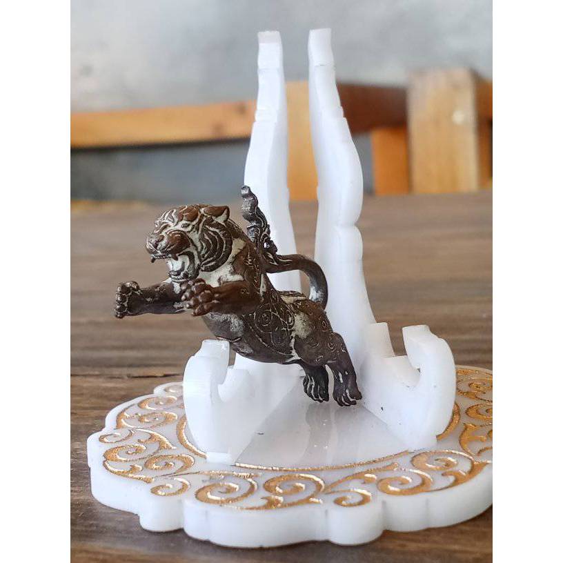 Bronze leaping tiger amulet on white decorative stand on wood table Thai Blessing Co Tiger Pern amulet for protection