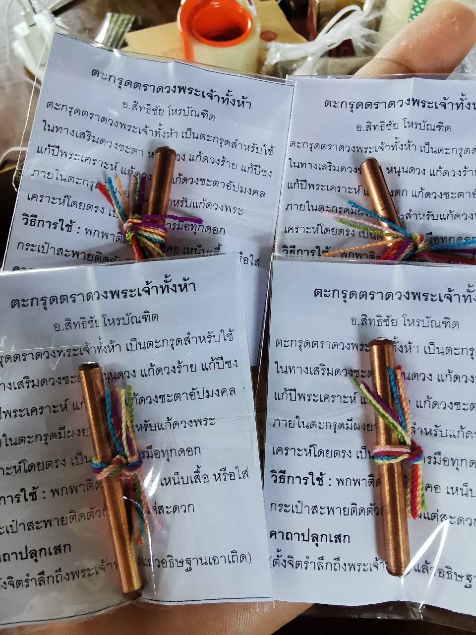 Four fortune boosting Thai talismans with colorful string ties and instructional cards for positive energy