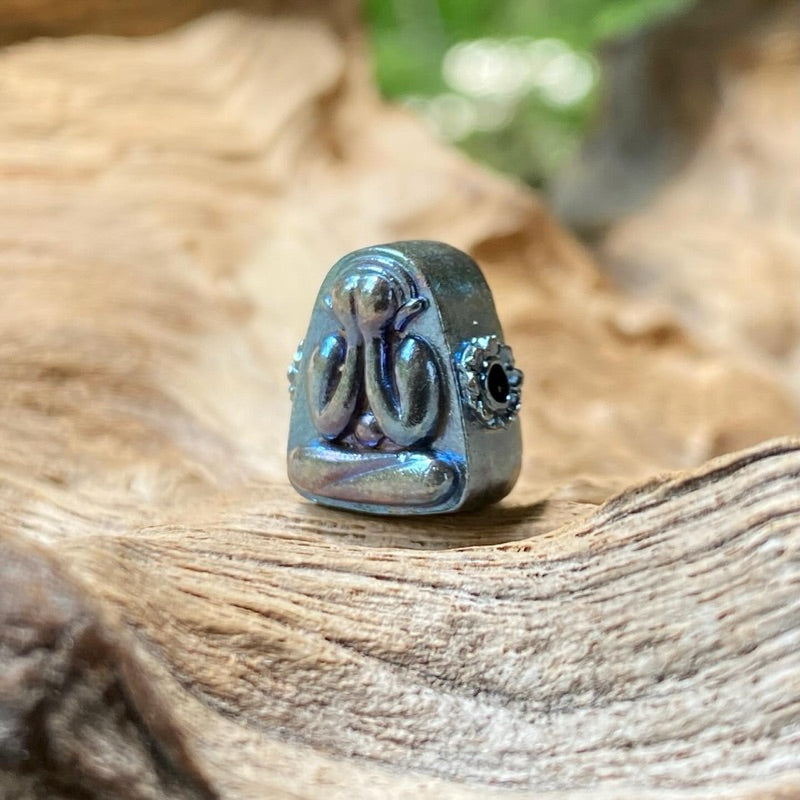 Blue tone Thai Buddhist amulet with detailed design placed on textured natural wood surface