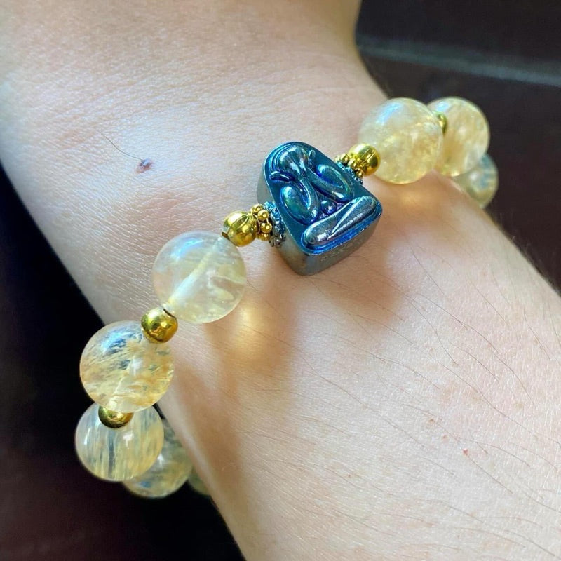 Blue tone Thai Buddhist amulet bracelet with translucent round beads and gold accents on wrist