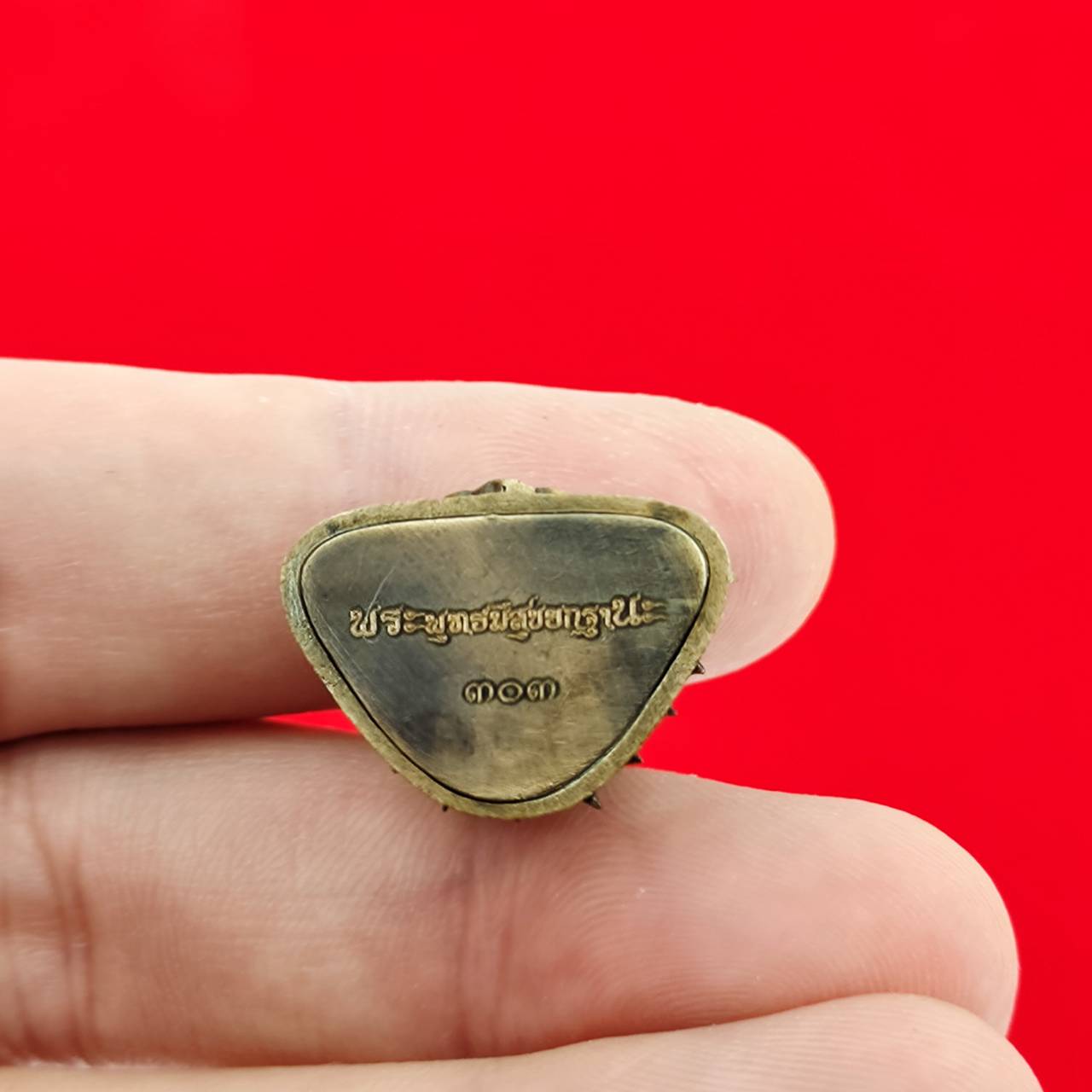 Thai Buddha amulet blessed by Luang Por Weera held in hand, showcasing its detailed design and inscription