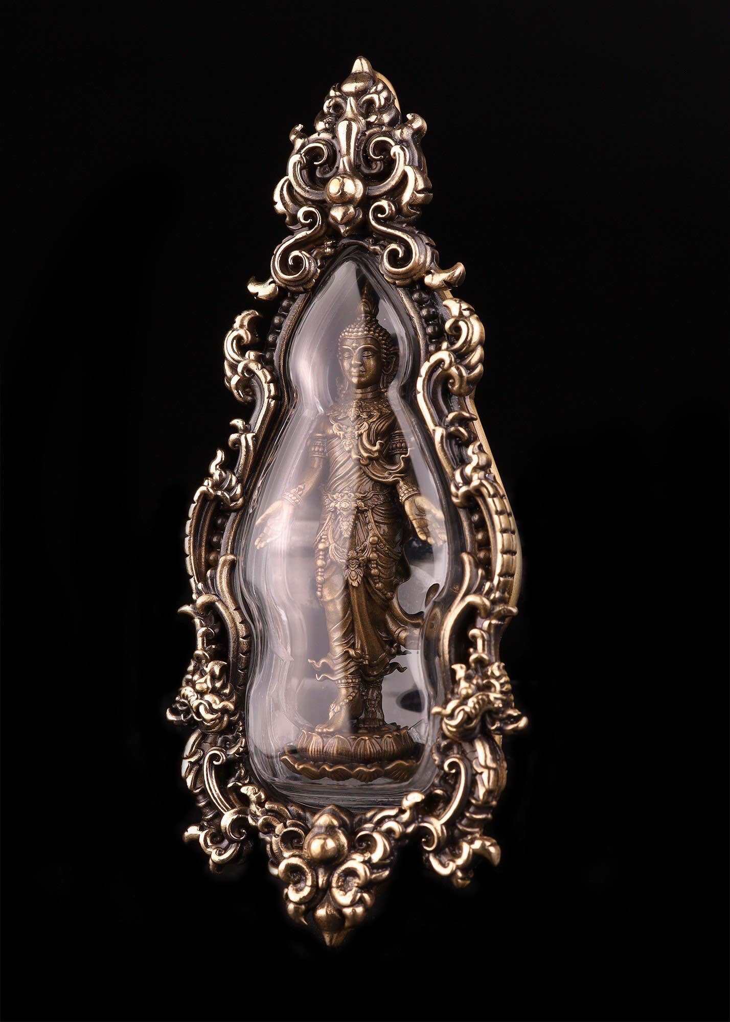 Ornate Thai Buddhist lucky charm featuring a protective figure encased in decorative glass and metal frame