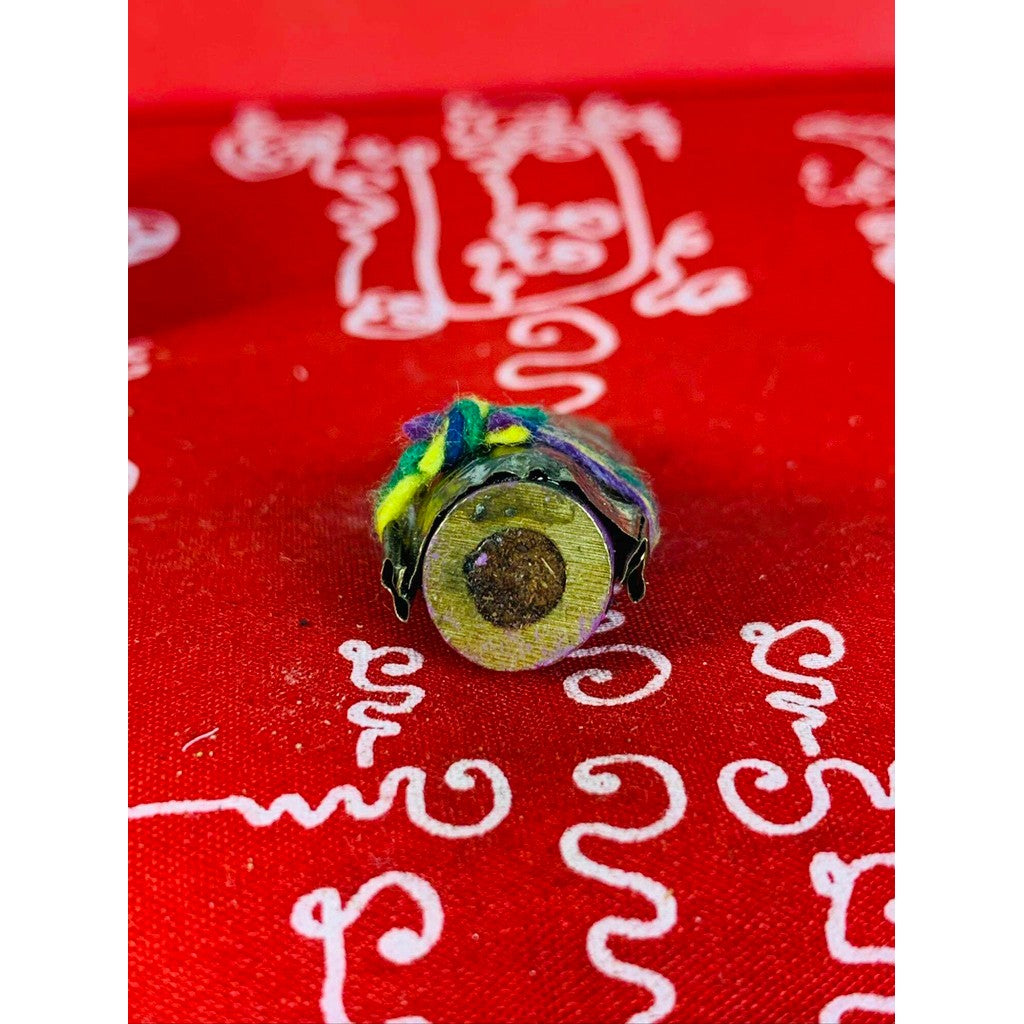 Thai business prosperity amulet with colorful fabric wrap on red cloth with white spiritual script