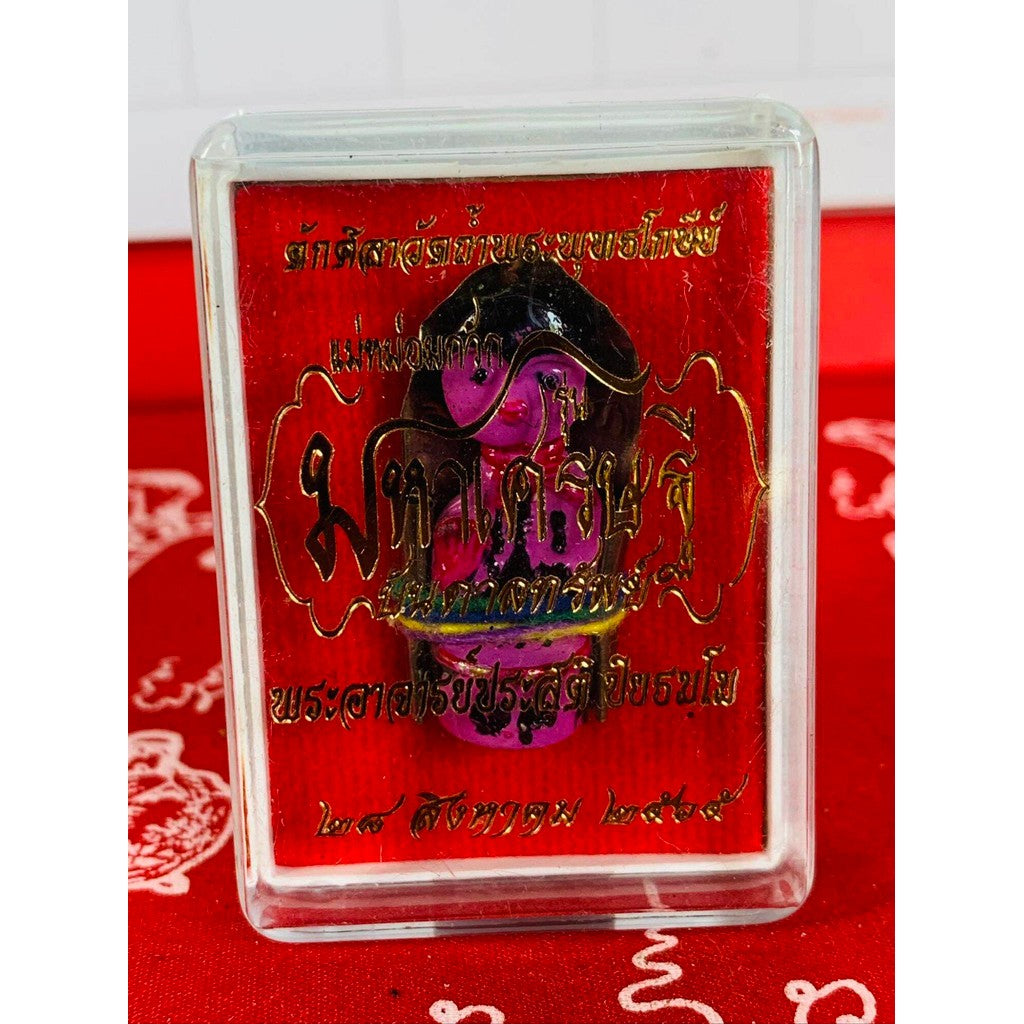 Thai business prosperity amulet encased in clear rectangular plastic with red background text