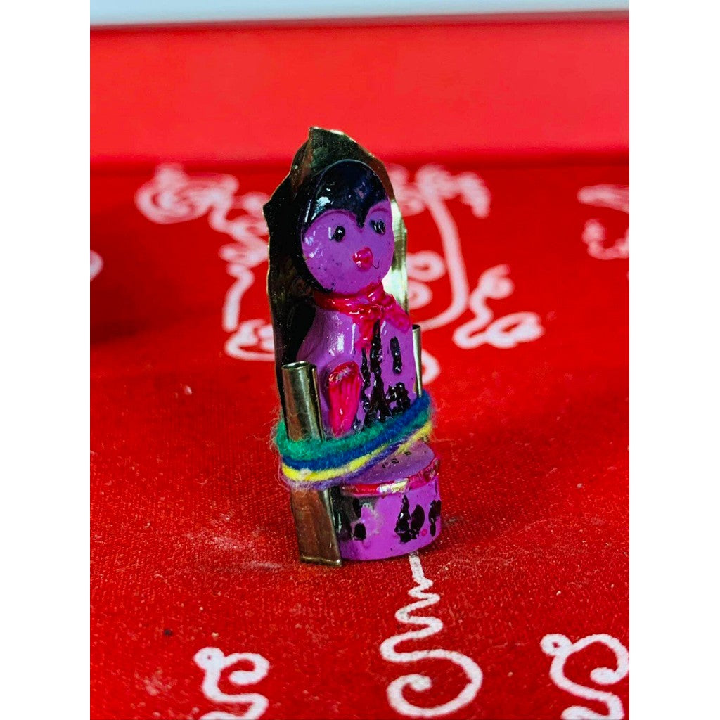 Thai business prosperity amulet with purple figure and colorful cloth wrap on red background