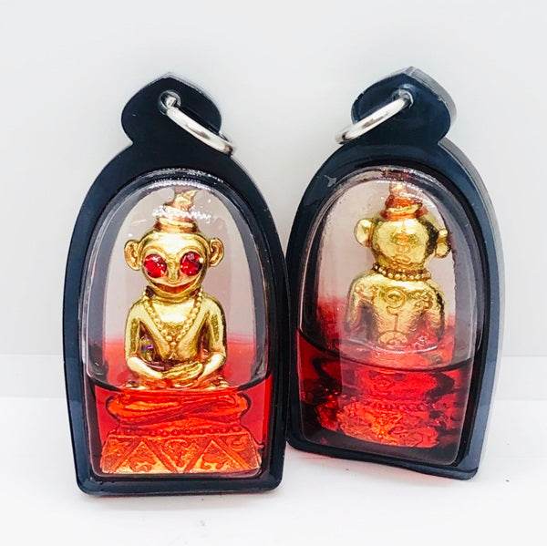 Thai charm amulet for luck featuring a golden figurine in a protective casing