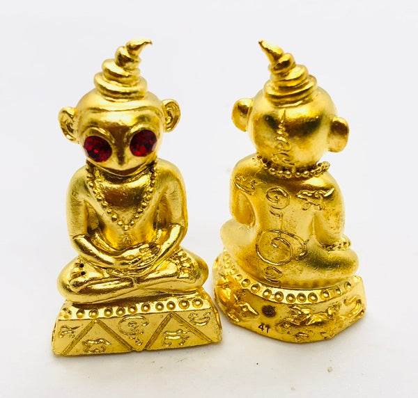 Golden Thai charm amulet for luck with red stones, detailed design, perfect for home décor