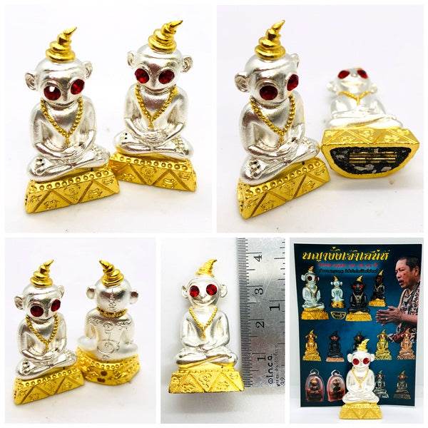 Thai charm amulet for luck featuring two shiny silver figurines with red eyes and golden accents