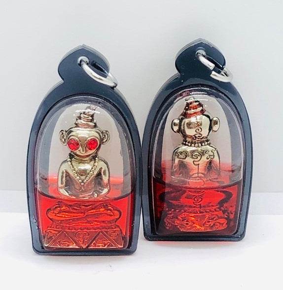Thai charm amulet for luck in a protective case with vibrant red color and golden figures