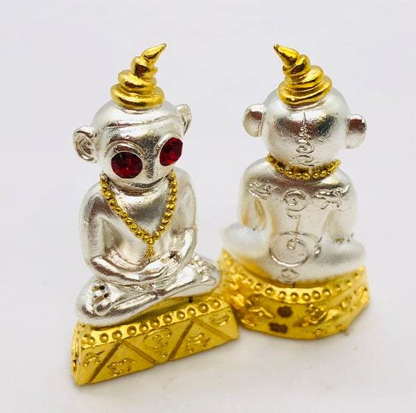 Thai charm amulet for luck featuring a detailed silver figurine with red eyes and gold accents