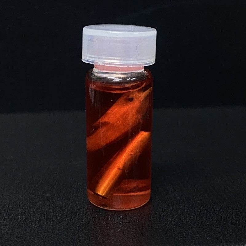 Small bottle of Thai charm oil for luck and popularity with a golden charm inside