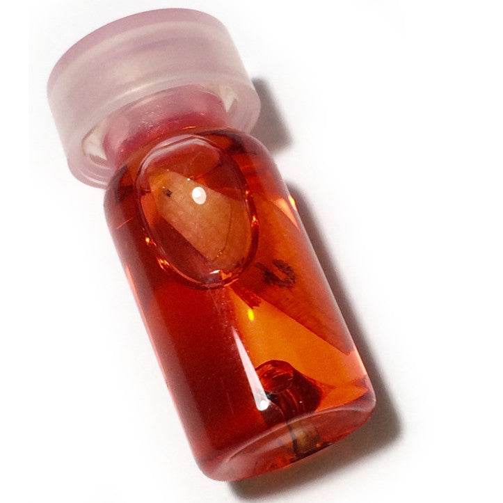Thai charm oil for luck and popularity in a small glass bottle with an amber hue