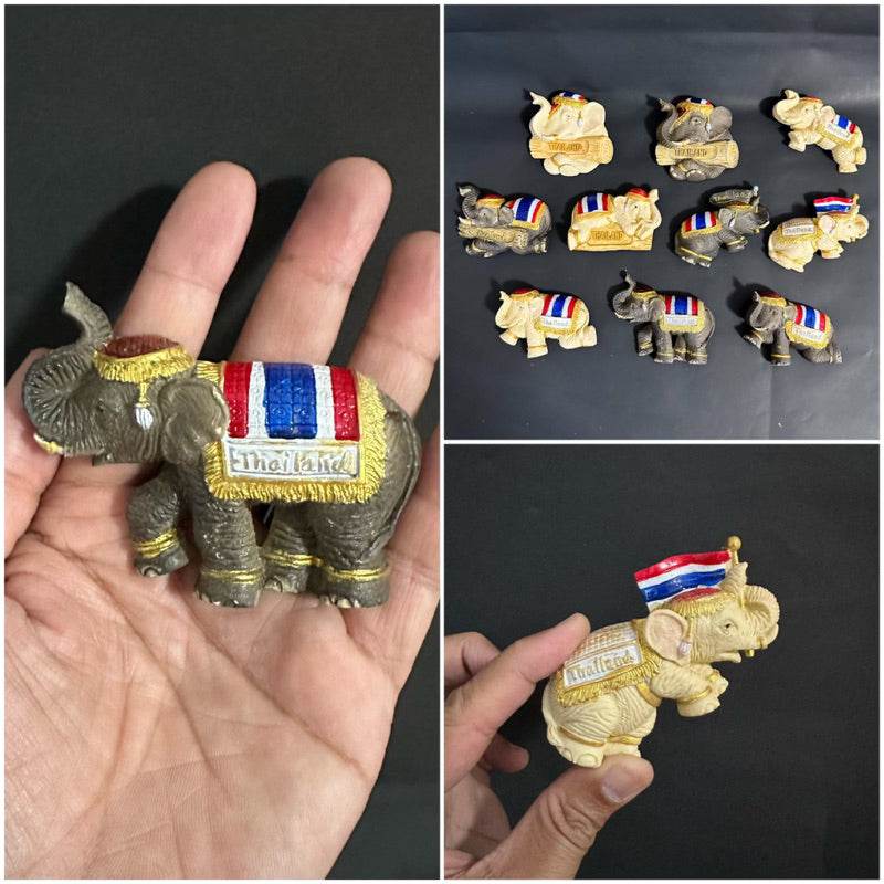 Set of Thai elephant fridge magnet souvenirs with colorful details held in hand and displayed on black background
