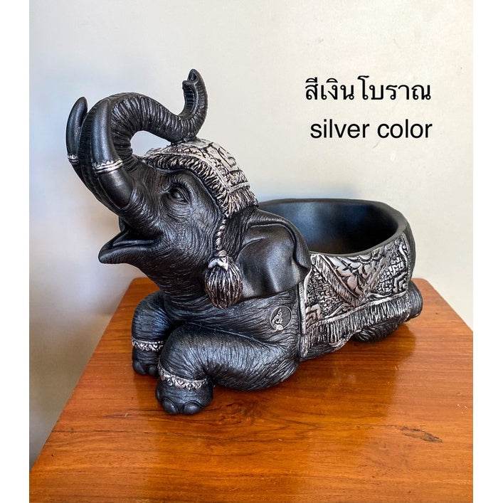 Silver color Thai elephant resin tray with detailed carving sitting on wooden table