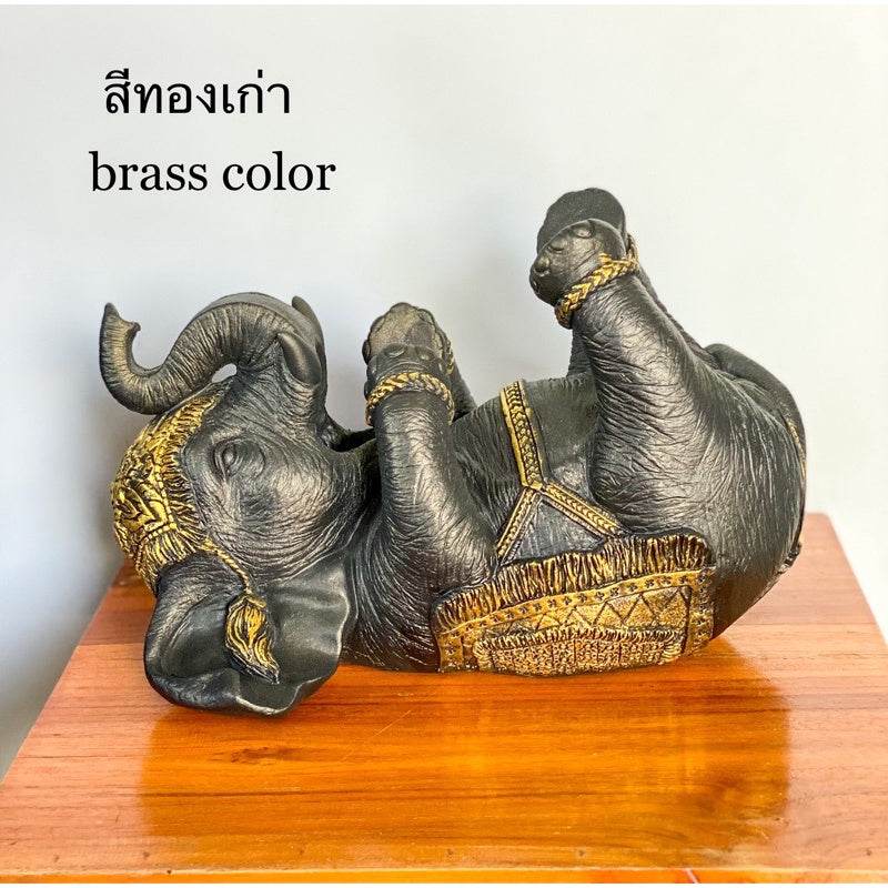 Brass color Thai elephant wine rack sculpture lying on its back on a wooden surface