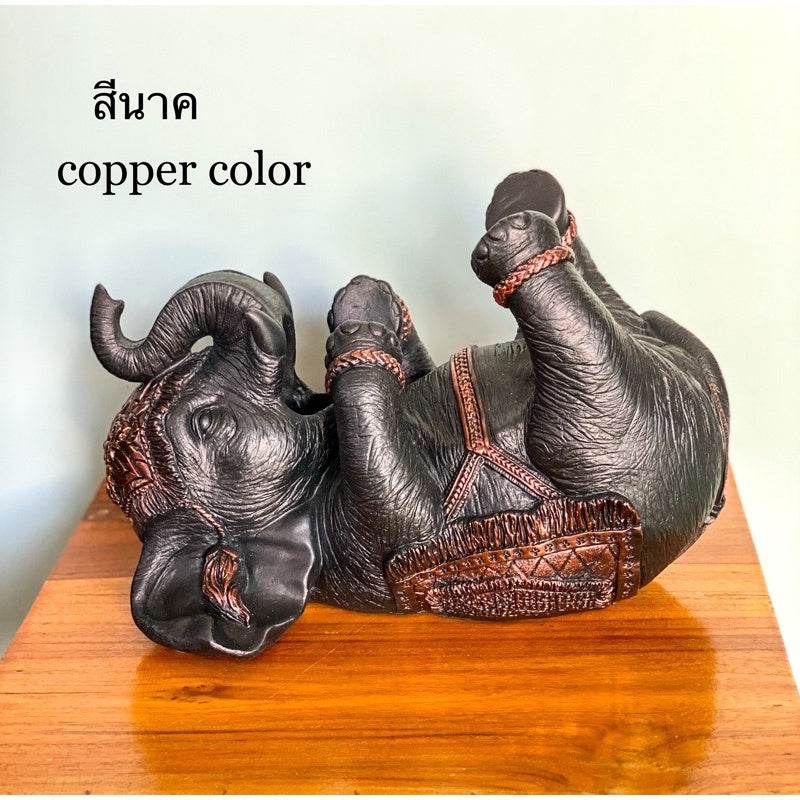 Copper color Thai elephant wine rack decorative piece lying on its back on wooden surface