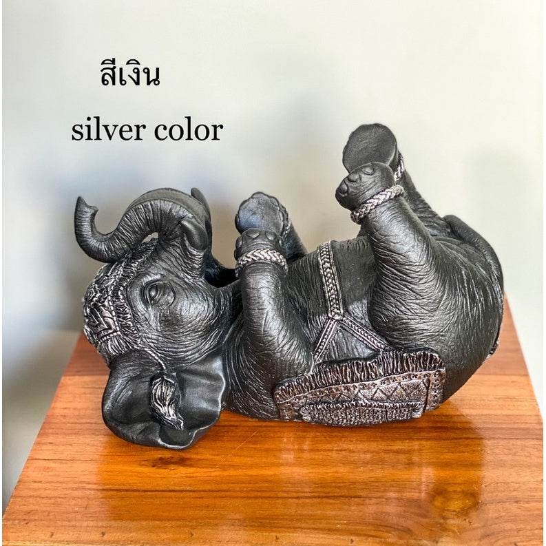 Silver color Thai elephant wine rack figurine lying on its back on wooden surface