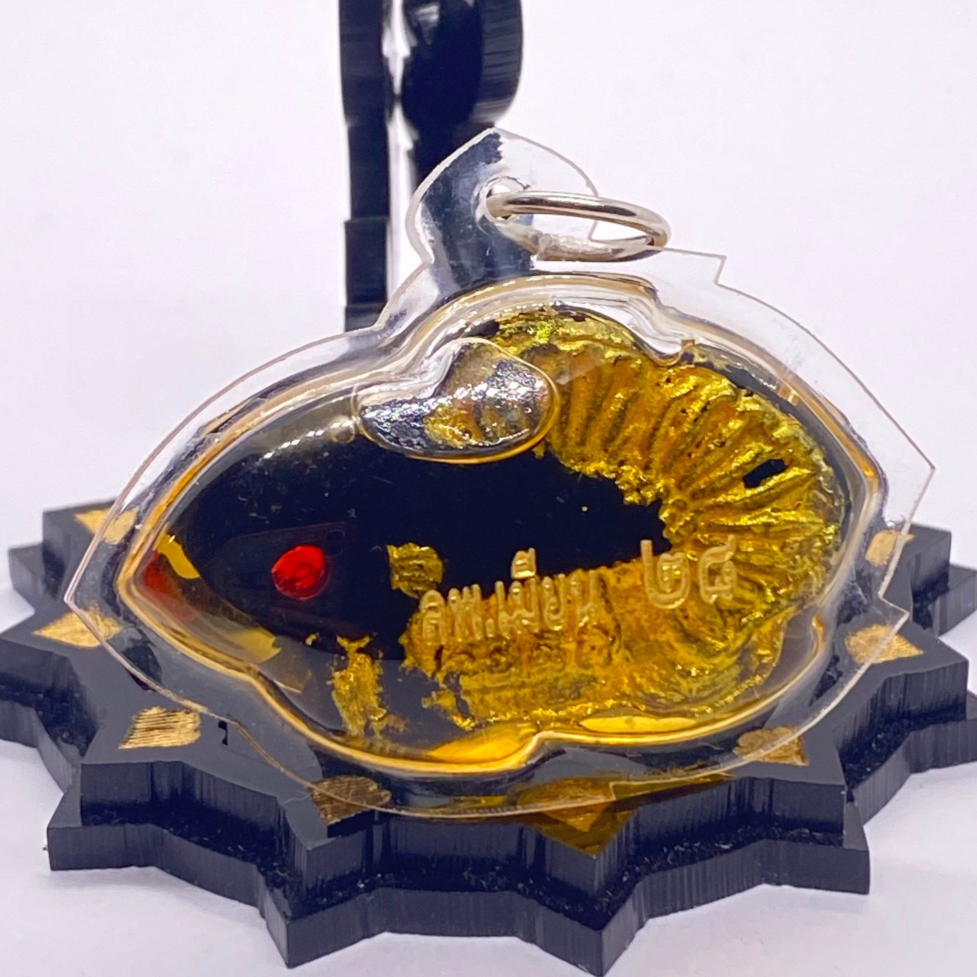 Thai fish amulet for protection and luck featuring a shiny gold and black design with a red detail
