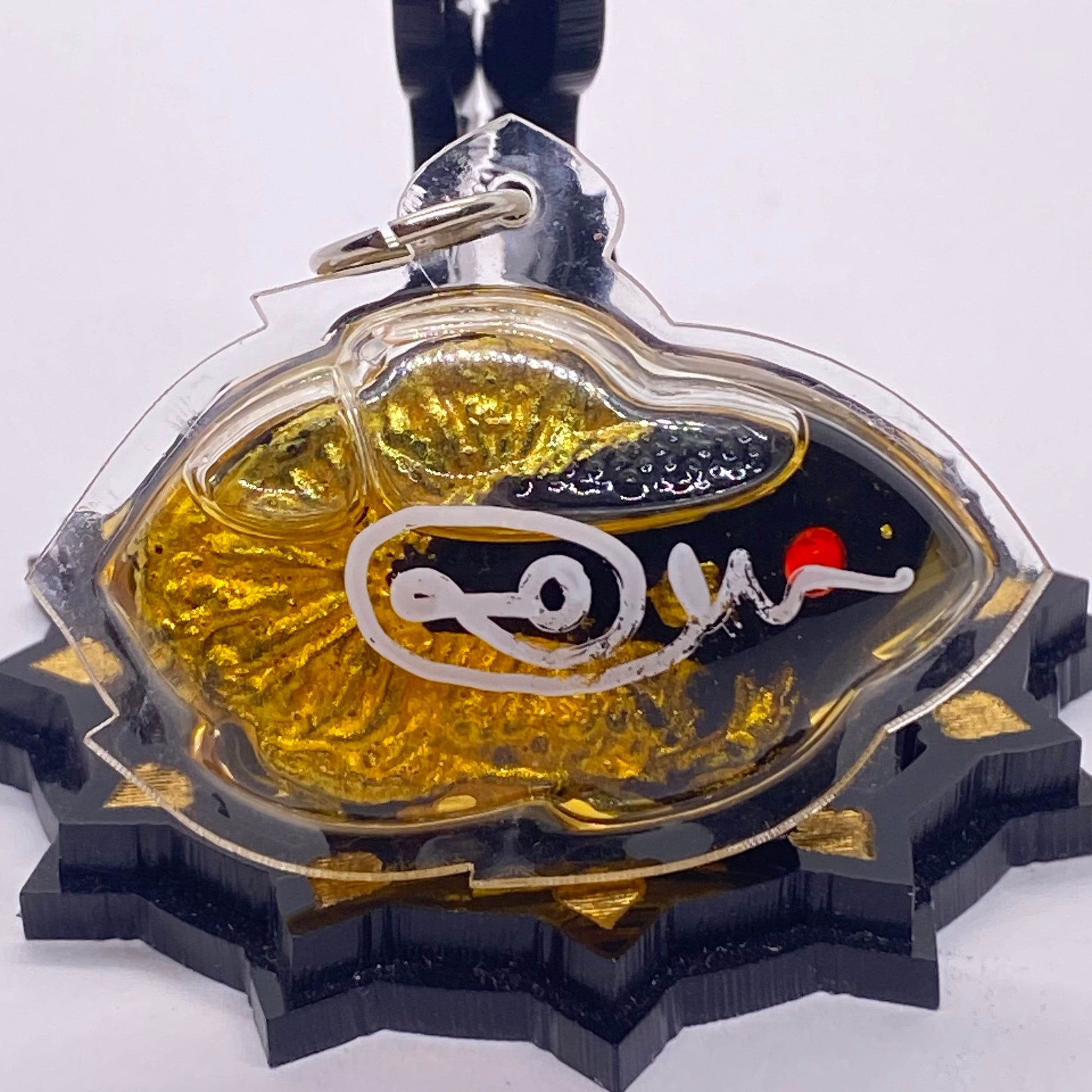 Thai fish amulet for protection and luck featuring a gold and black design with intricate detailing