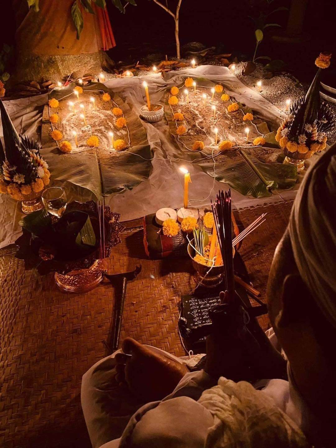 Traditional Thai ceremony setup with candles and flowers featuring Thai gambler's takrud amulet ritual