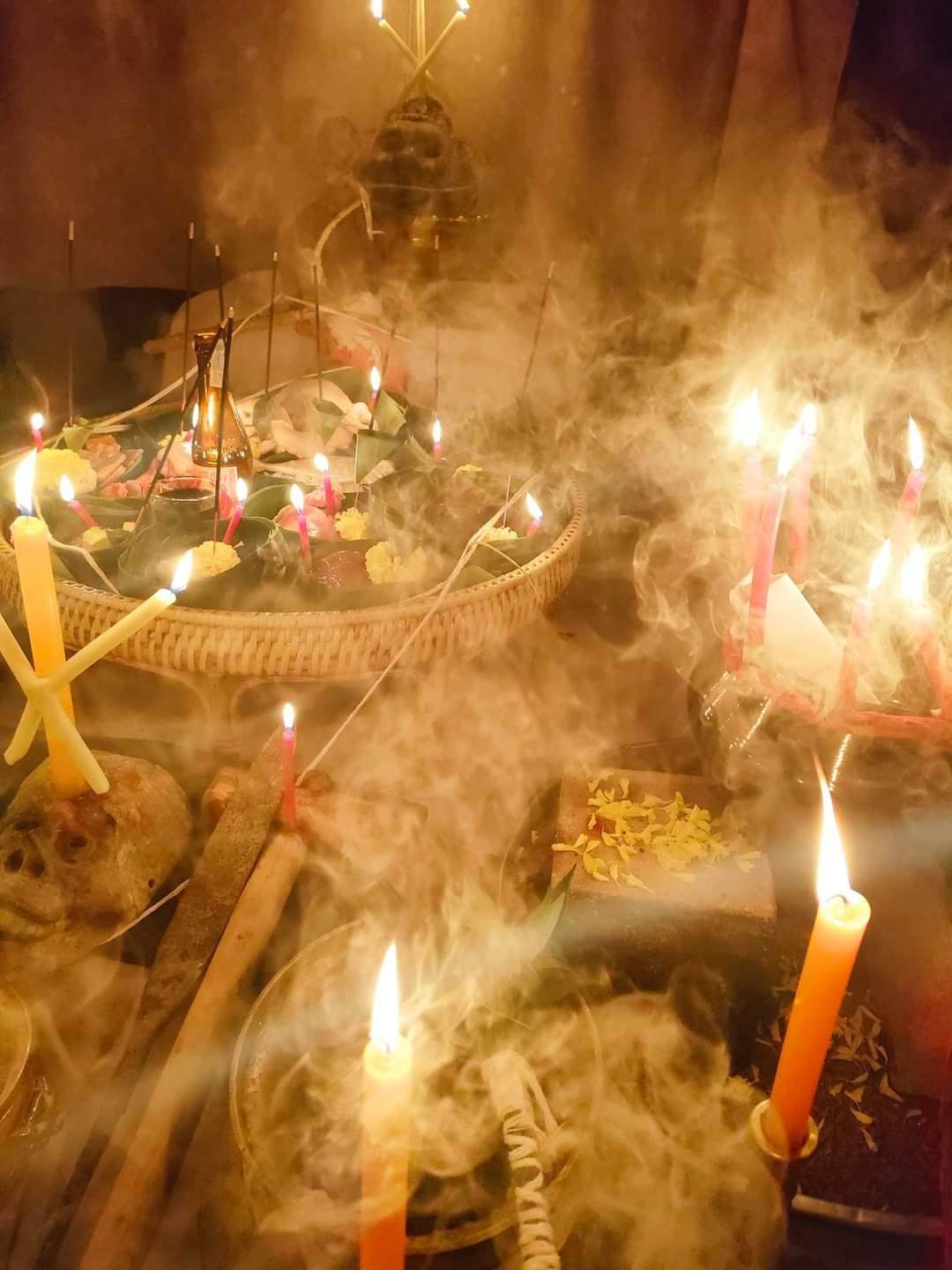 Mystical setting with candles and incense smoke surrounding a Thai gambler's takrud amulet ritual