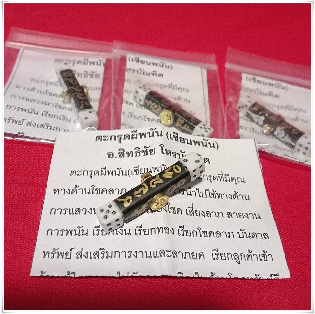 Thai gambler's takrud amulet with gold inscriptions in protective plastic bag on red background