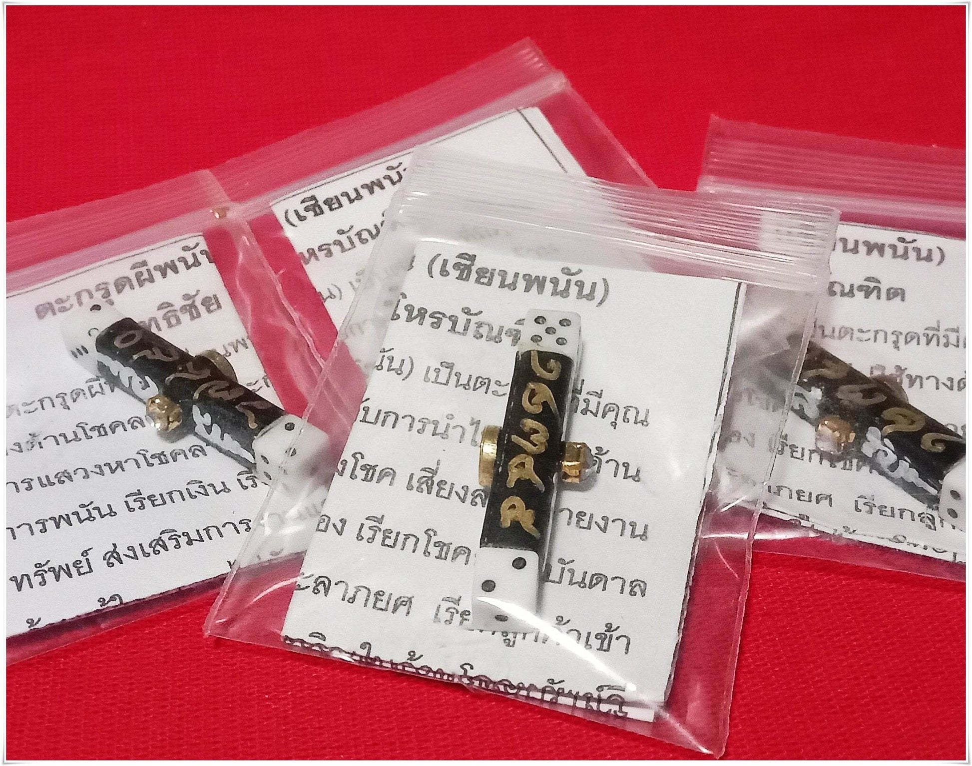 Thai gambler's takrud amulet with dice in clear plastic bags on red background from Thai Blessing Co