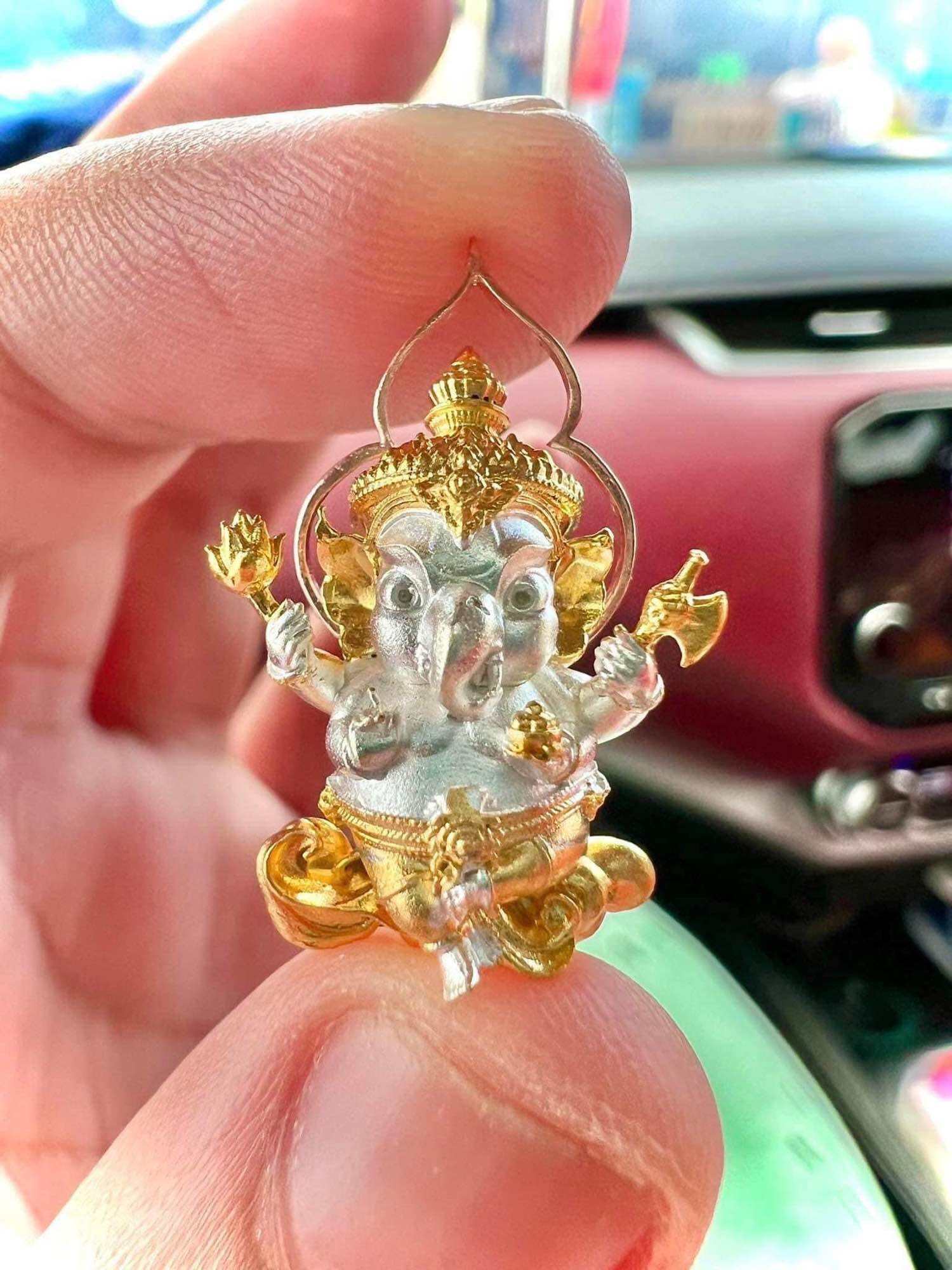 Thai Ganesha amulet for wealth in intricate design held between fingers, ideal for attracting prosperity