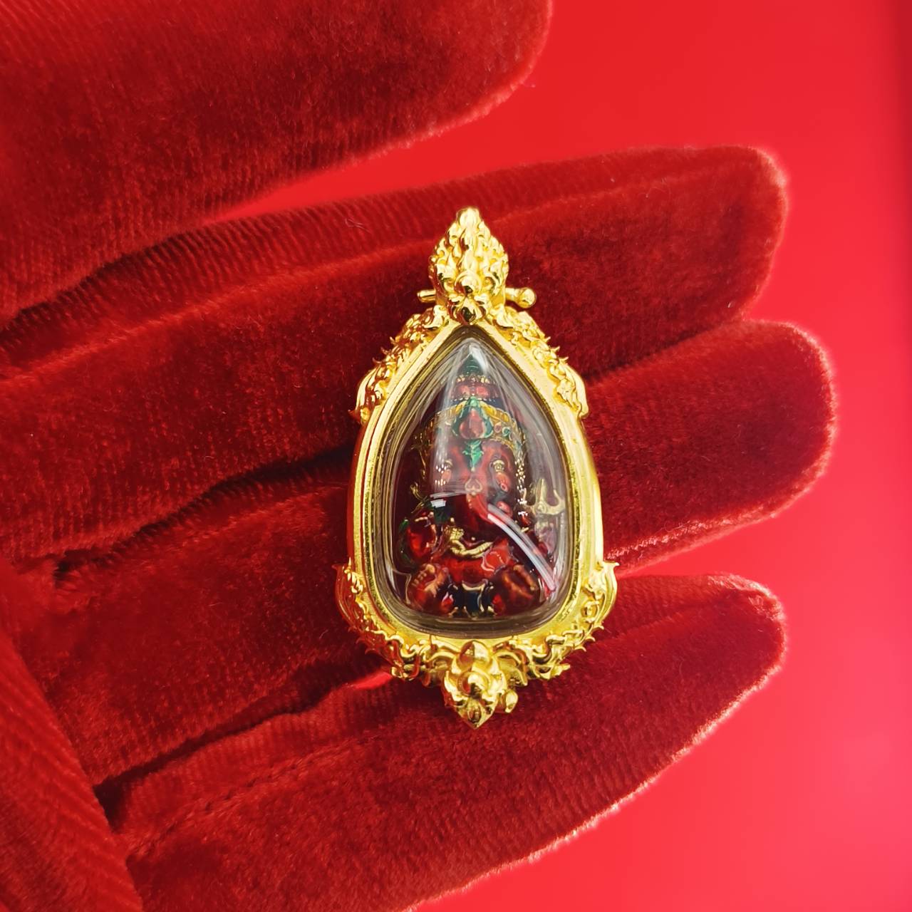 Thai Ganesha pendant for success in a golden frame, set against a vibrant red background