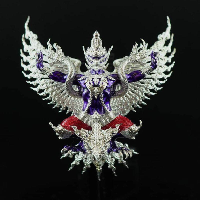Intricate silver and purple Thai Garuda lucky charm with detailed wings and red accents on black background