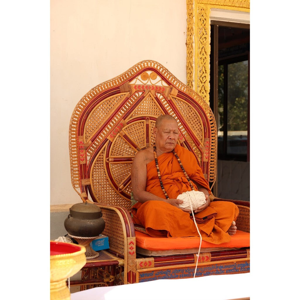 Thai monk blessing a Thai goddess amulet for prosperity in a serene temple setting