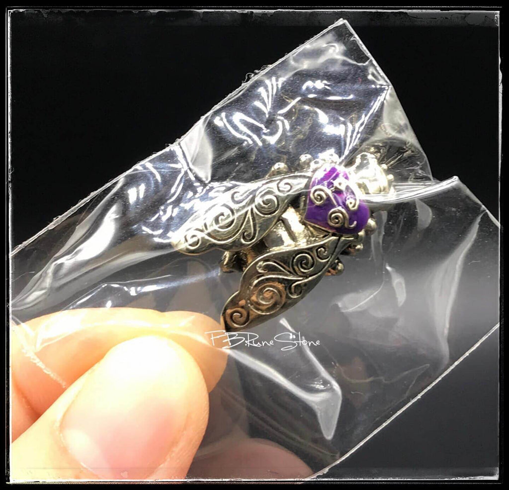 Thai golden bee amulet for wealth with intricate silver detailing held in clear packaging