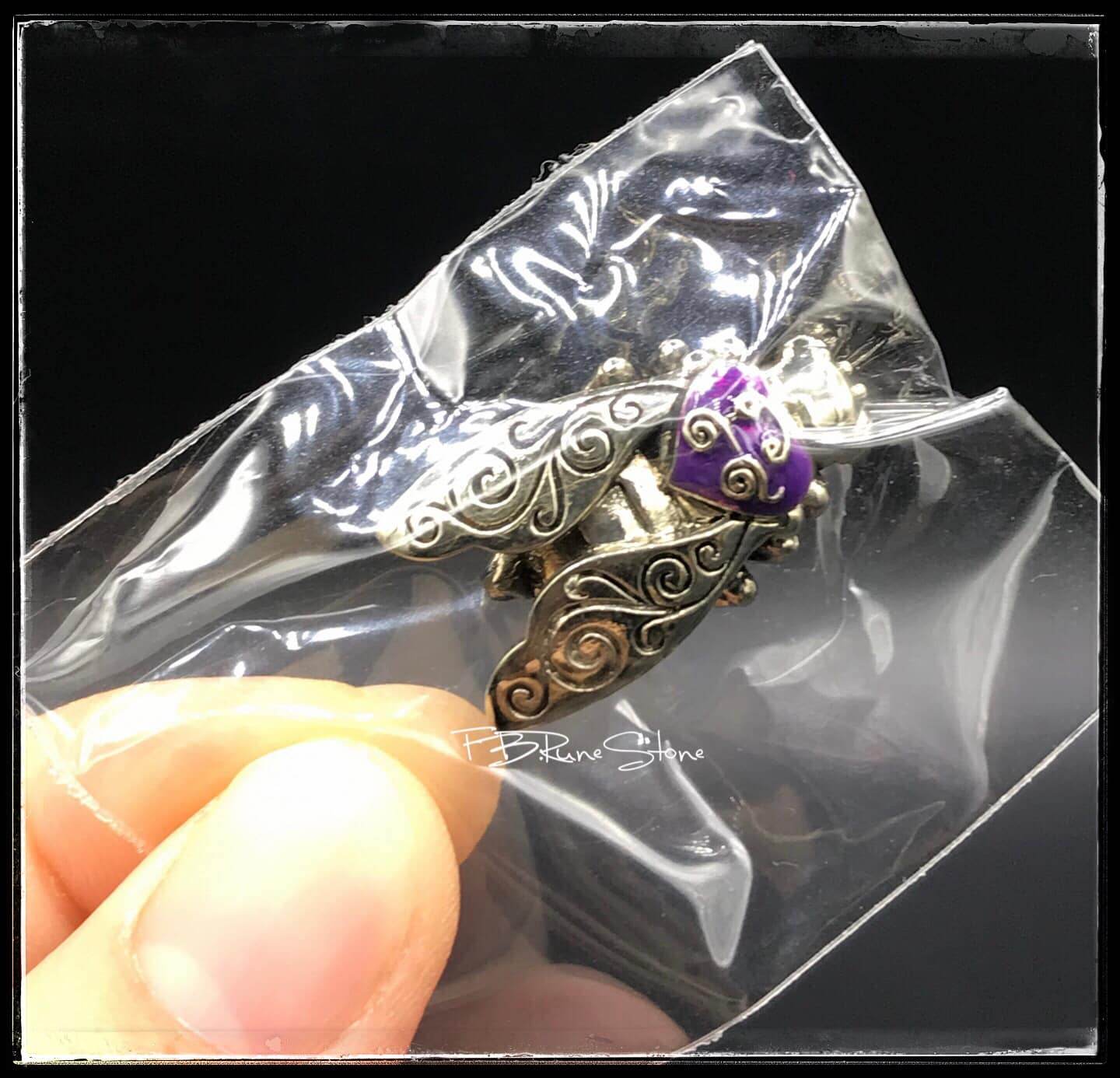 Thai golden bee amulet for wealth with intricate silver detailing held in clear packaging