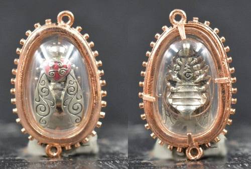 Thai golden bee amulet for wealth with intricate silver and gold design encased in clear resin
