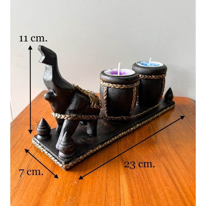 Thai handcrafted home decor black elephant candle holder with two candles on wooden surface