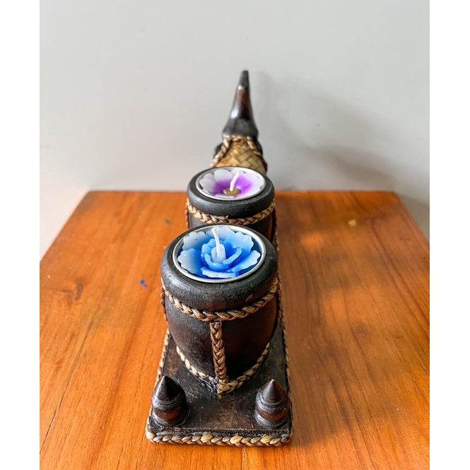 Thai handcrafted home decor wooden candle holder with two flower-shaped candles on wooden surface