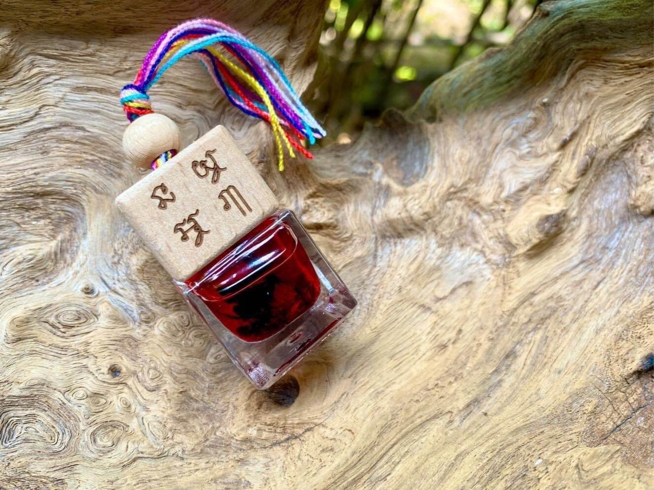 Thai herb blessing oil bottle with wooden cap and colorful tassel on natural wood surface