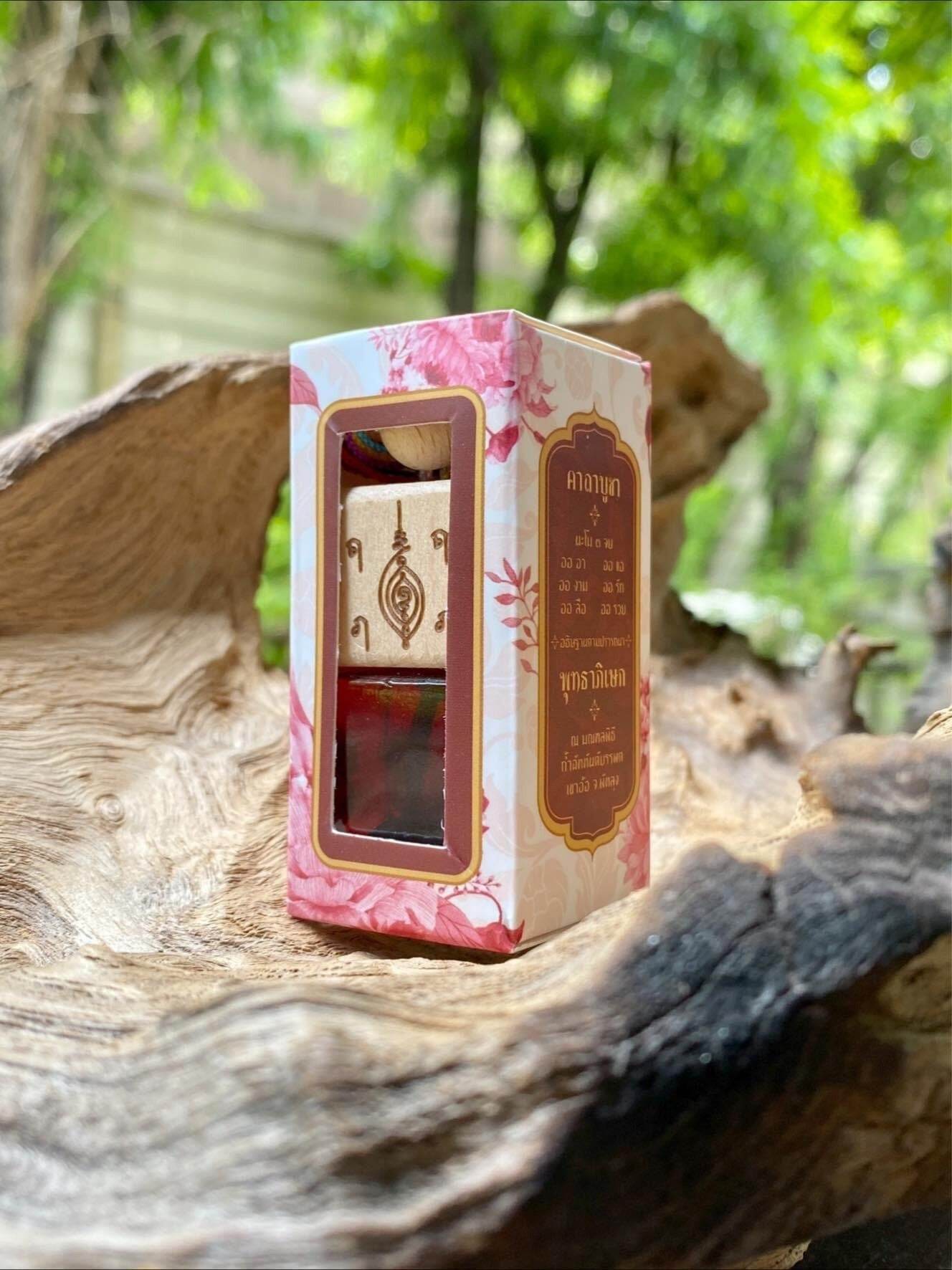Thai herb blessing oil by Thai Blessing Co in decorative floral box placed on rustic wood outdoors