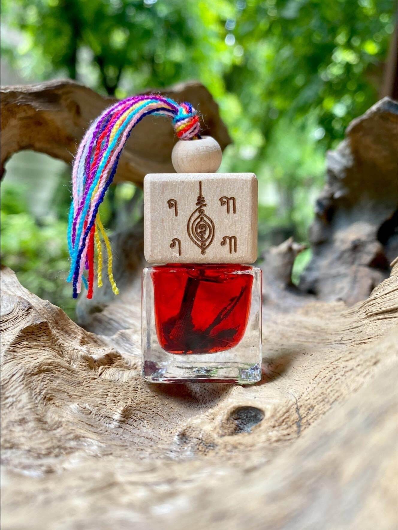 Thai herb blessing oil in a clear glass bottle with wooden cap and colorful tassel on natural wood background