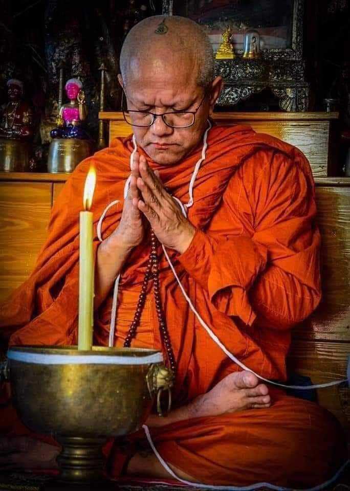 Thai monk praying with Jin-Da-Mani magical bead amulet pendant during temple blessing ritual
