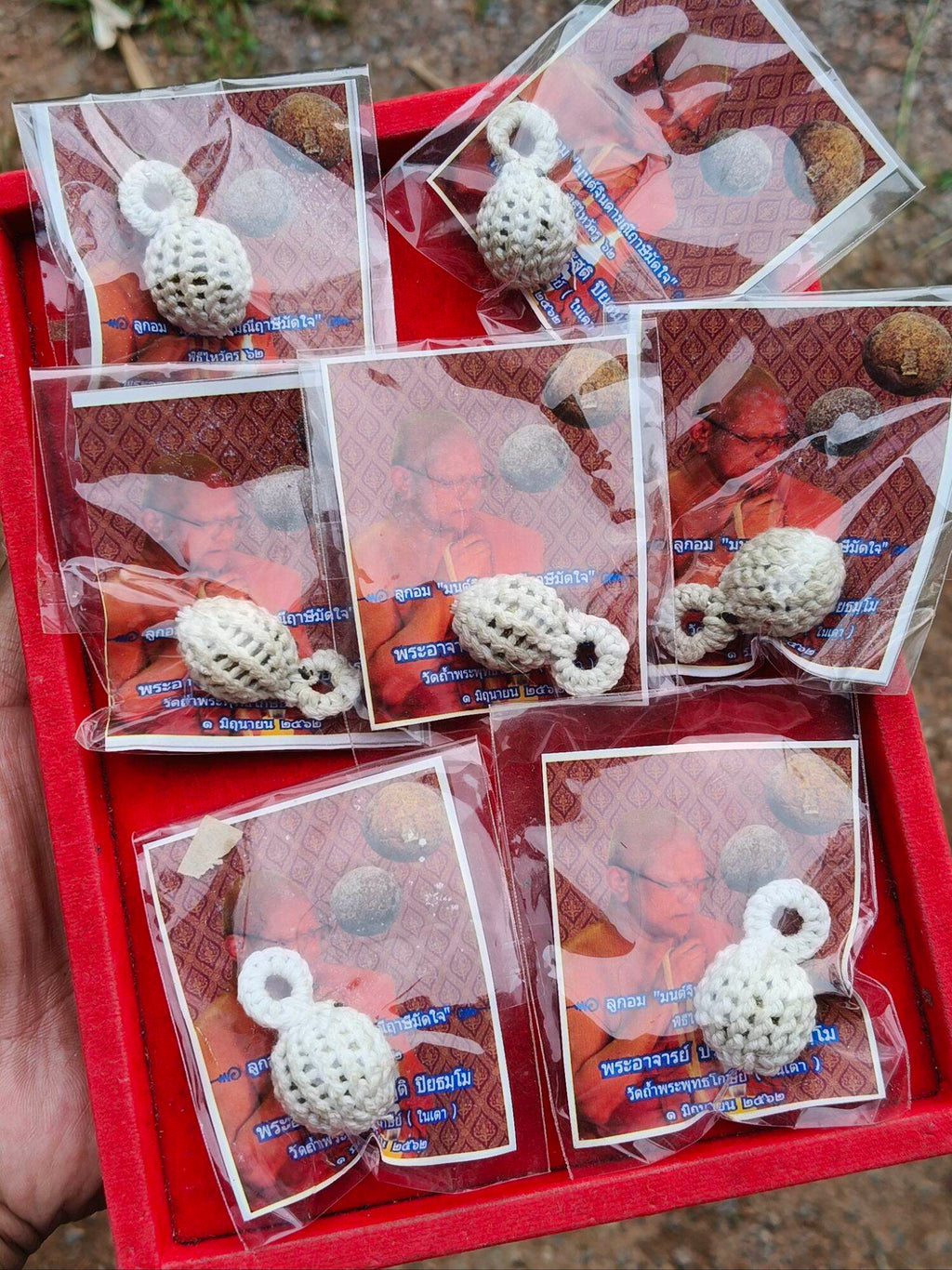 Thai Blessing Co Jin-Da-Mani magical bead amulet white crocheted pendants packaged on cards in red tray