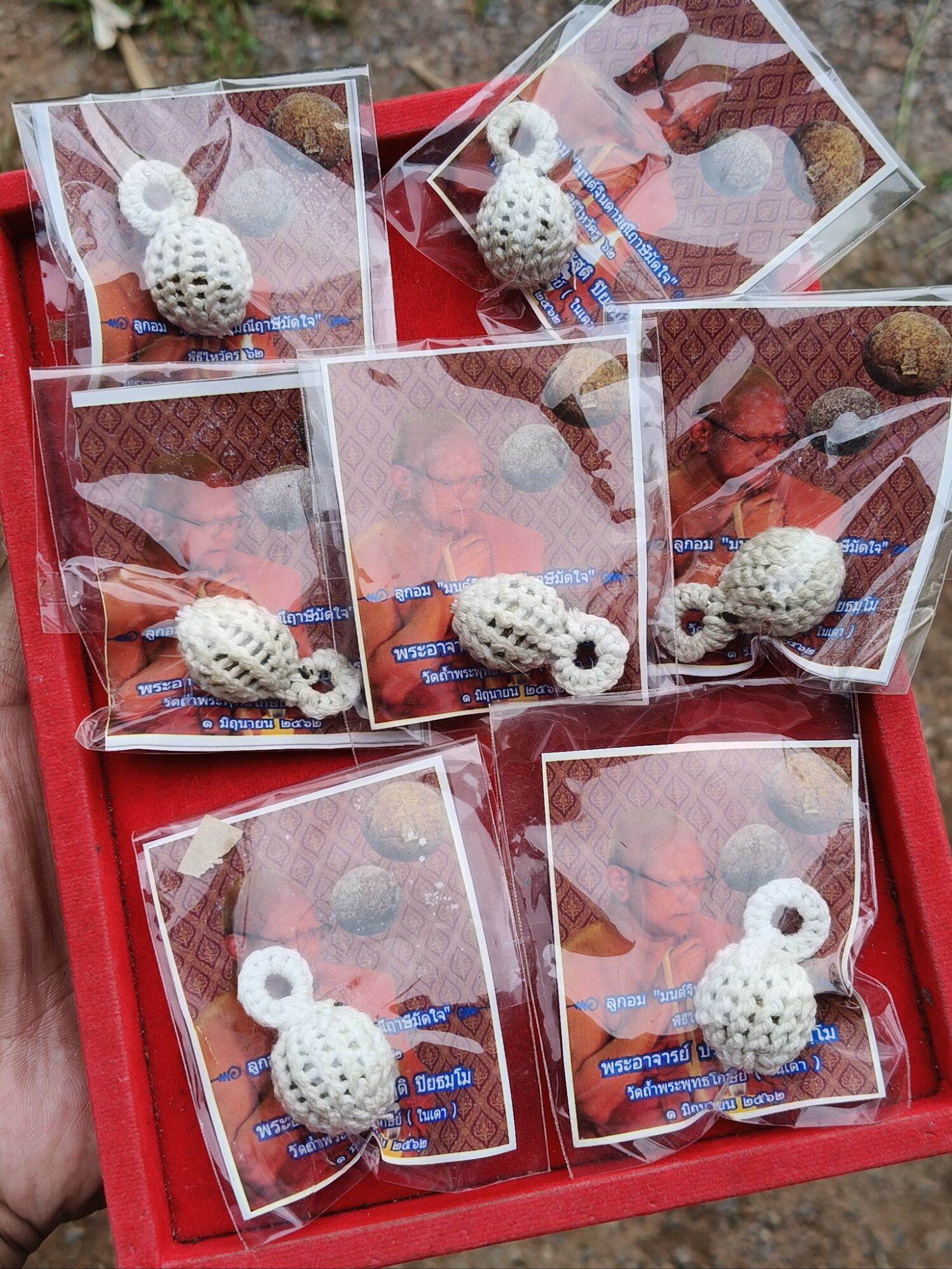Thai Blessing Co Jin-Da-Mani magical bead amulet white crocheted pendants packaged on cards in red tray
