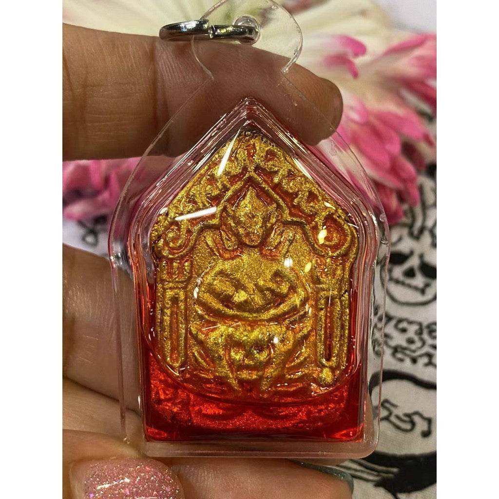 Thai Khun Paen red oil amulet in a protective casing, showcasing intricate design and vibrant colors.