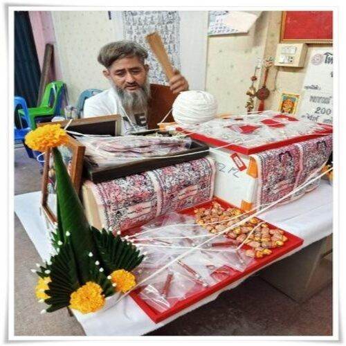 Thai love talisman cloth displayed on a table with offerings and a practitioner performing rituals