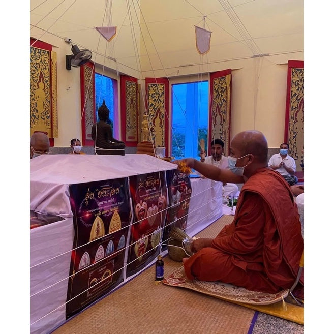 Thai Buddhist monk blessing Thai luck amulet for victory inside temple with followers