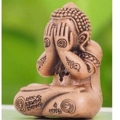 Thai lucky charm for prosperity with seated Buddha figure covering face in meditation pose