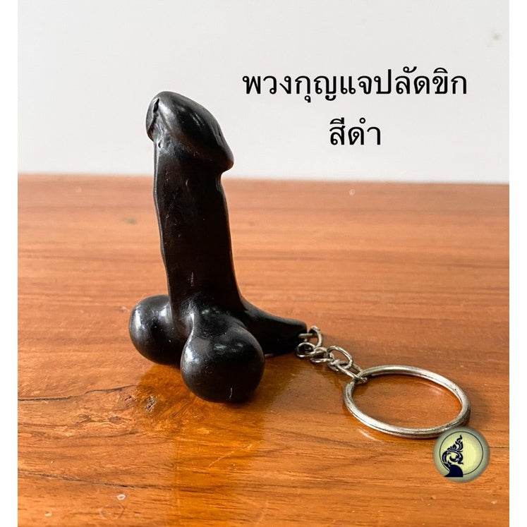 One-Sake.com black Thai lucky keychain shaped like a phallic charm on a wooden surface