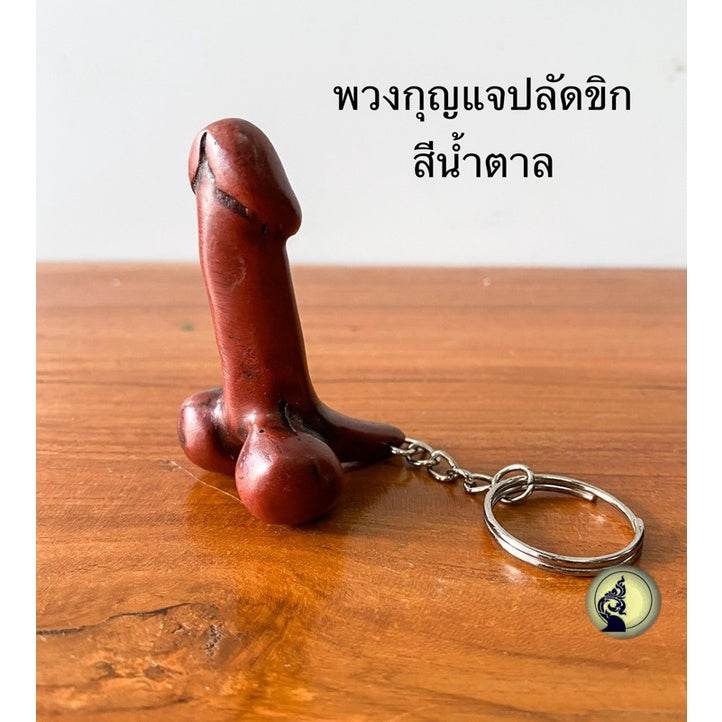 Thai lucky keychain in brown wood shaped uniquely on wooden surface from One-Sake.com